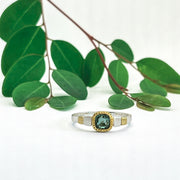 A silver band ring with a square bezel setting containing a green topaz.