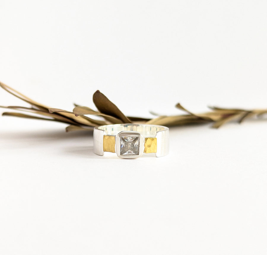 A square zircon gemstone ring with hammered sterling silver links and a wide plain brass band.