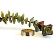 A sterling silver ring with a square garnet stone, positioned on a plain brass band.