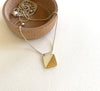 A small square pendant with a diagonal half plated in 18ct gold. Made in 925 sterling silver, fine dash-lines have been carefully incised to the gold layer as well.